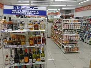 A liquor store aisle with various alcohol brands and a sign indicating a legal age verification requirement.