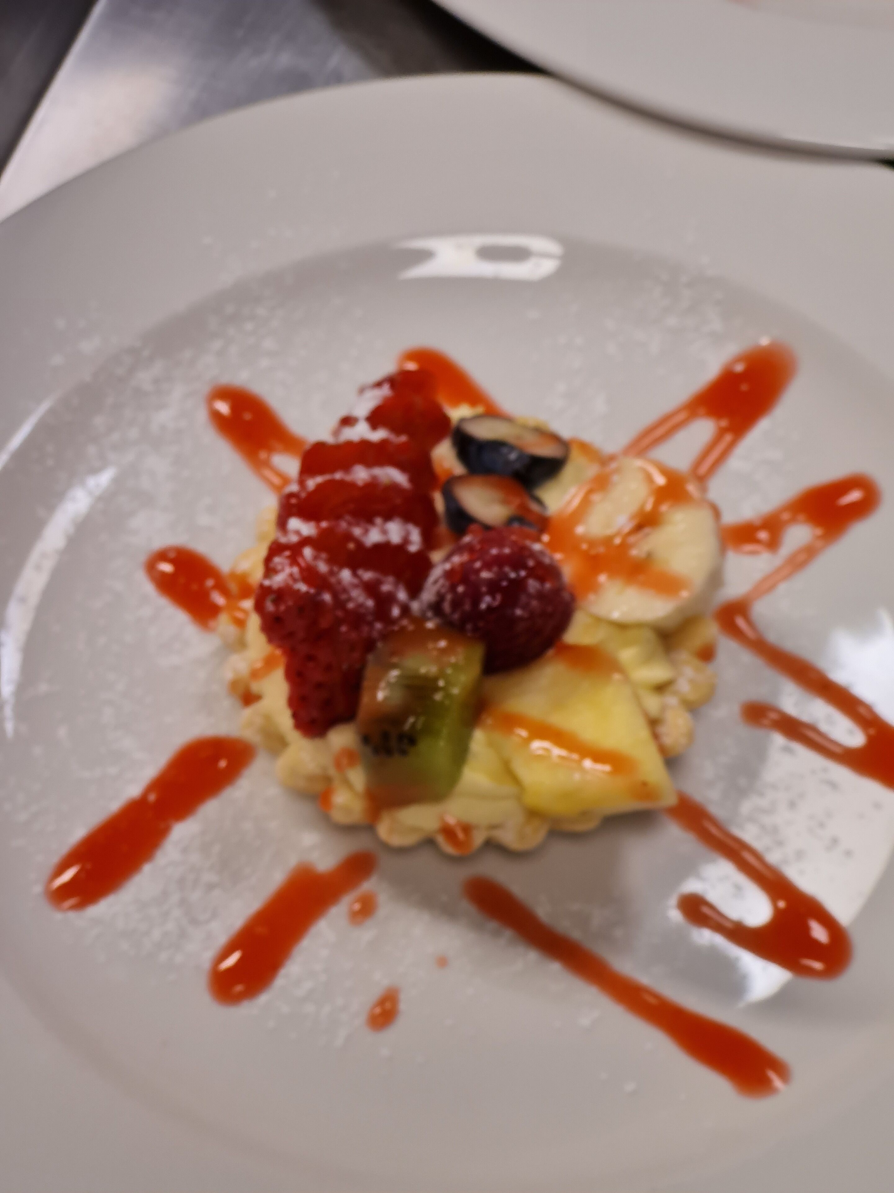 Un plato de postre con fruta y salsa.