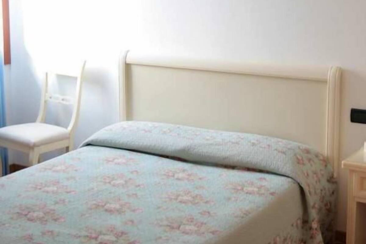 A bedroom with a bed, a chair, and a bedside table.