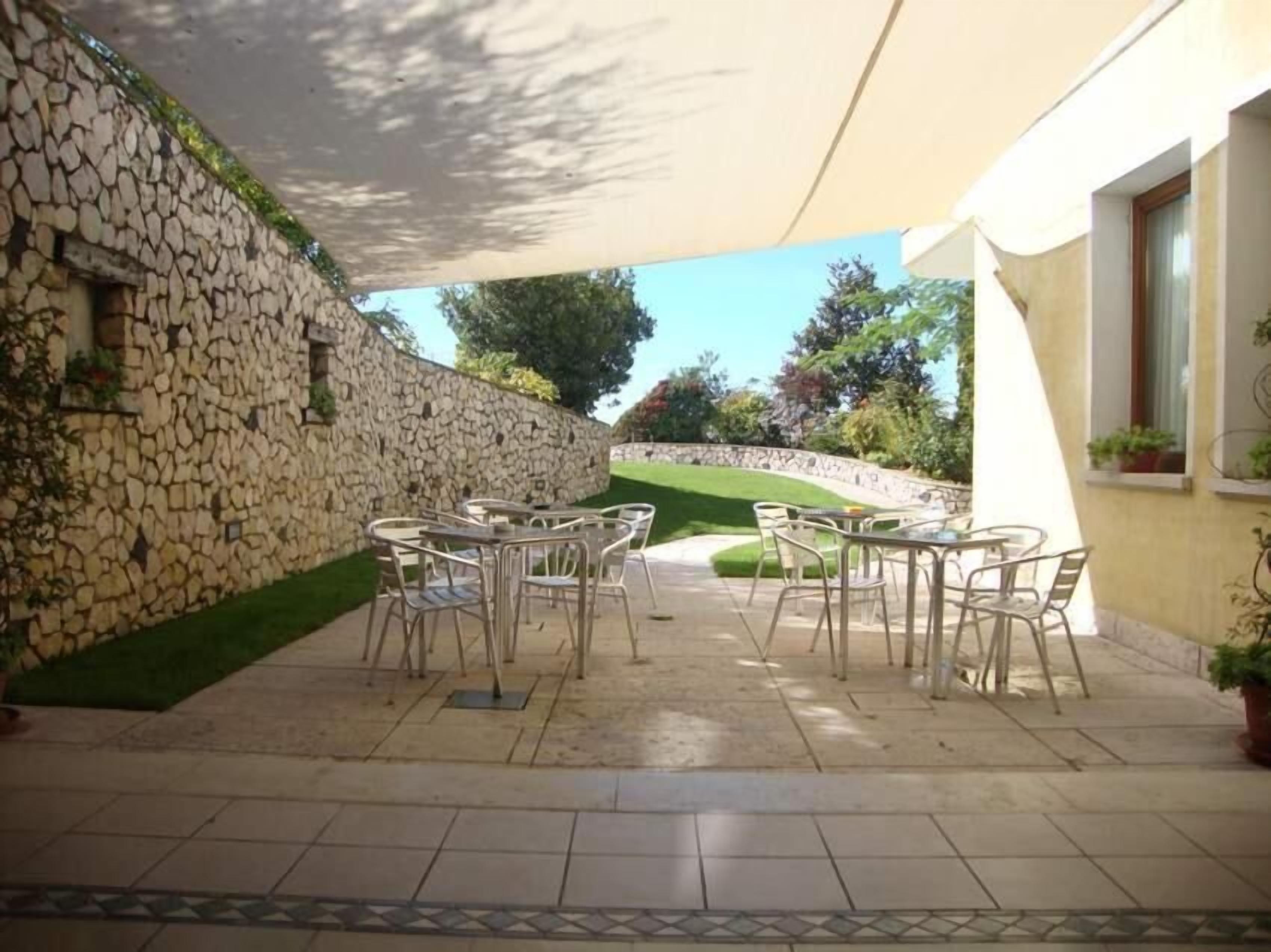 Eine Terrasse im Freien mit Steinmauern, gefliestem Boden und Metallstühlen.