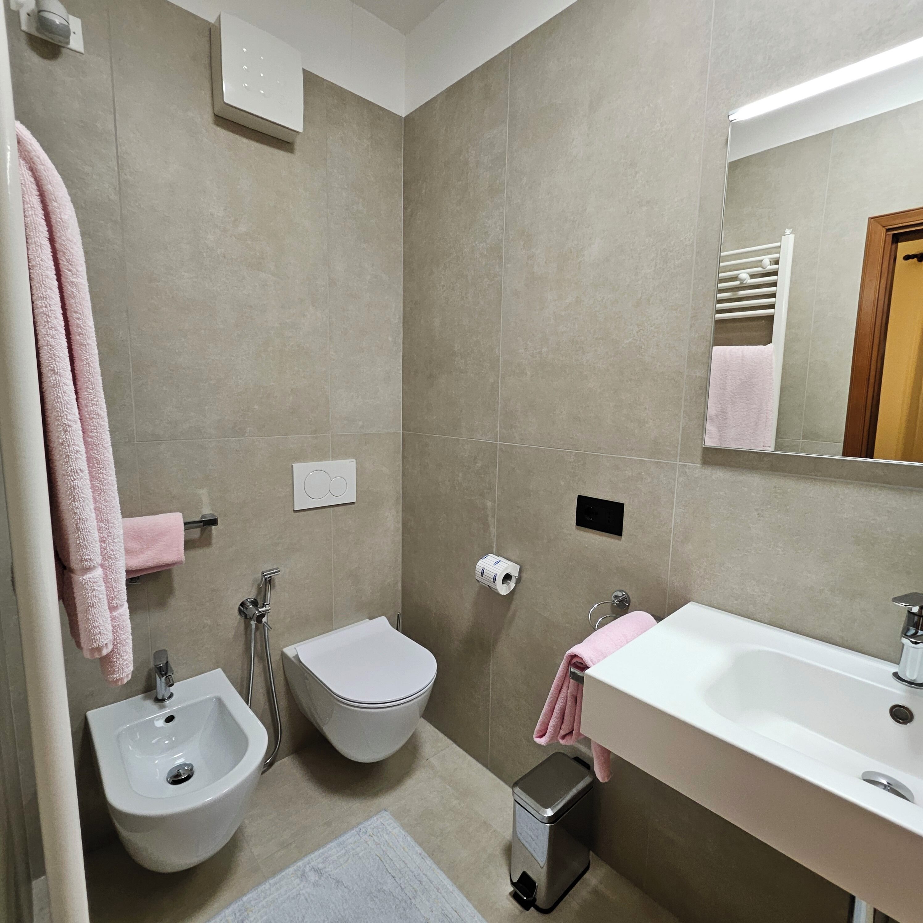 Une salle de bain moderne équipée d’un bidet, de toilettes, d’un lavabo et d’un miroir.