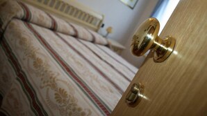 Quarto com uma cama, uma porta de madeira e um radiador.