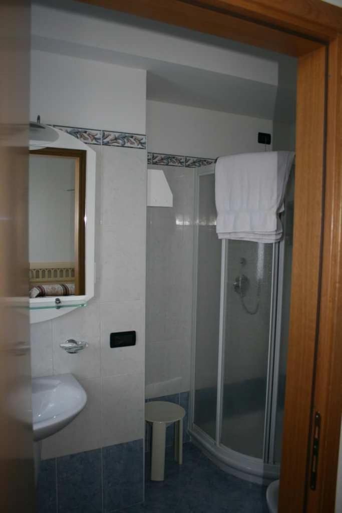 A bathroom with a sink, mirror, and a glass-enclosed shower.