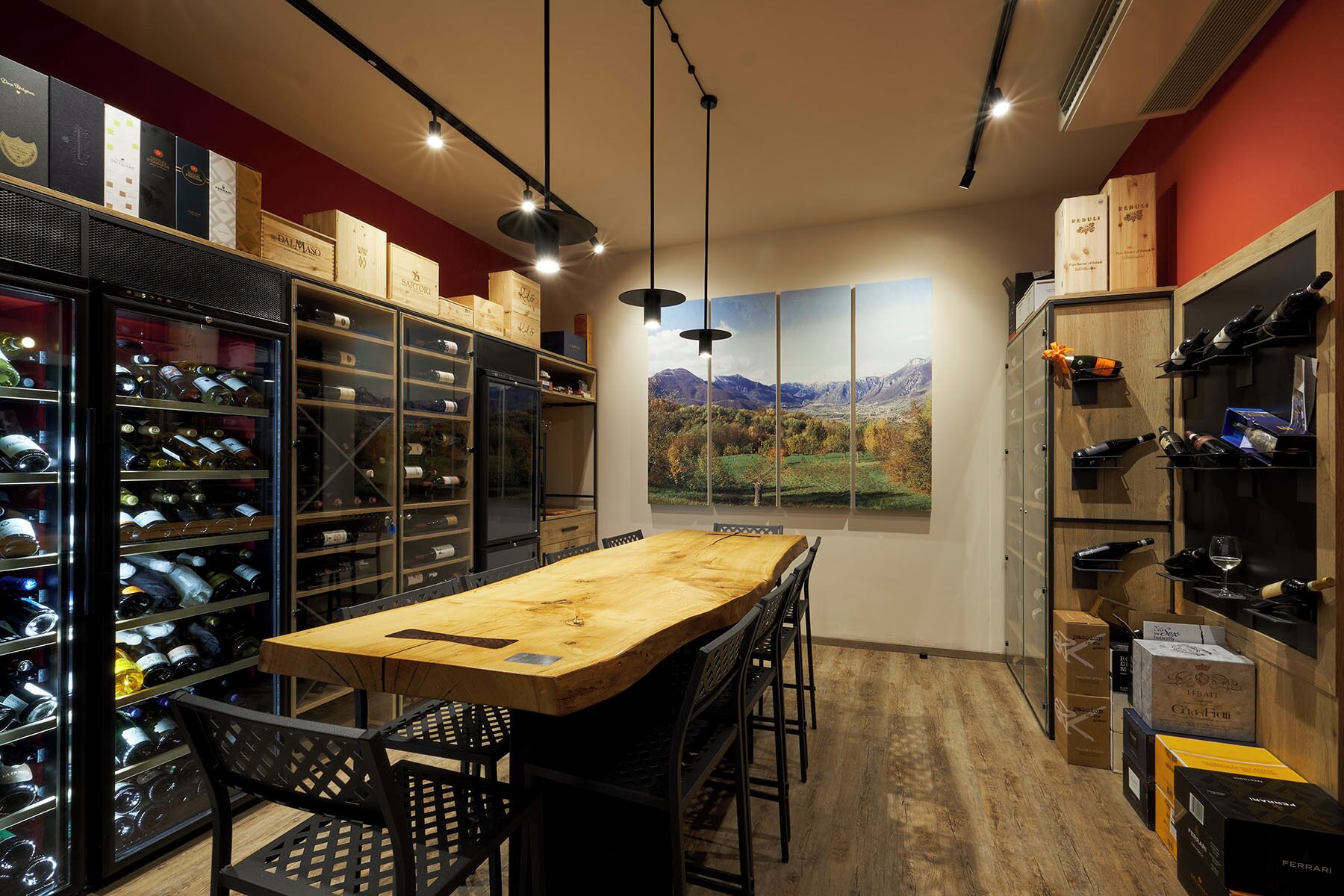 A wine cellar with wooden shelves, a large wooden table, and a view of mountains through a window.
