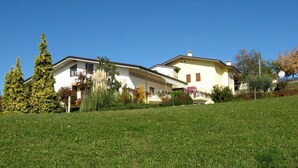 Uma casa de dois andares com telhado inclinado, varanda frontal e gramado bem cuidado.