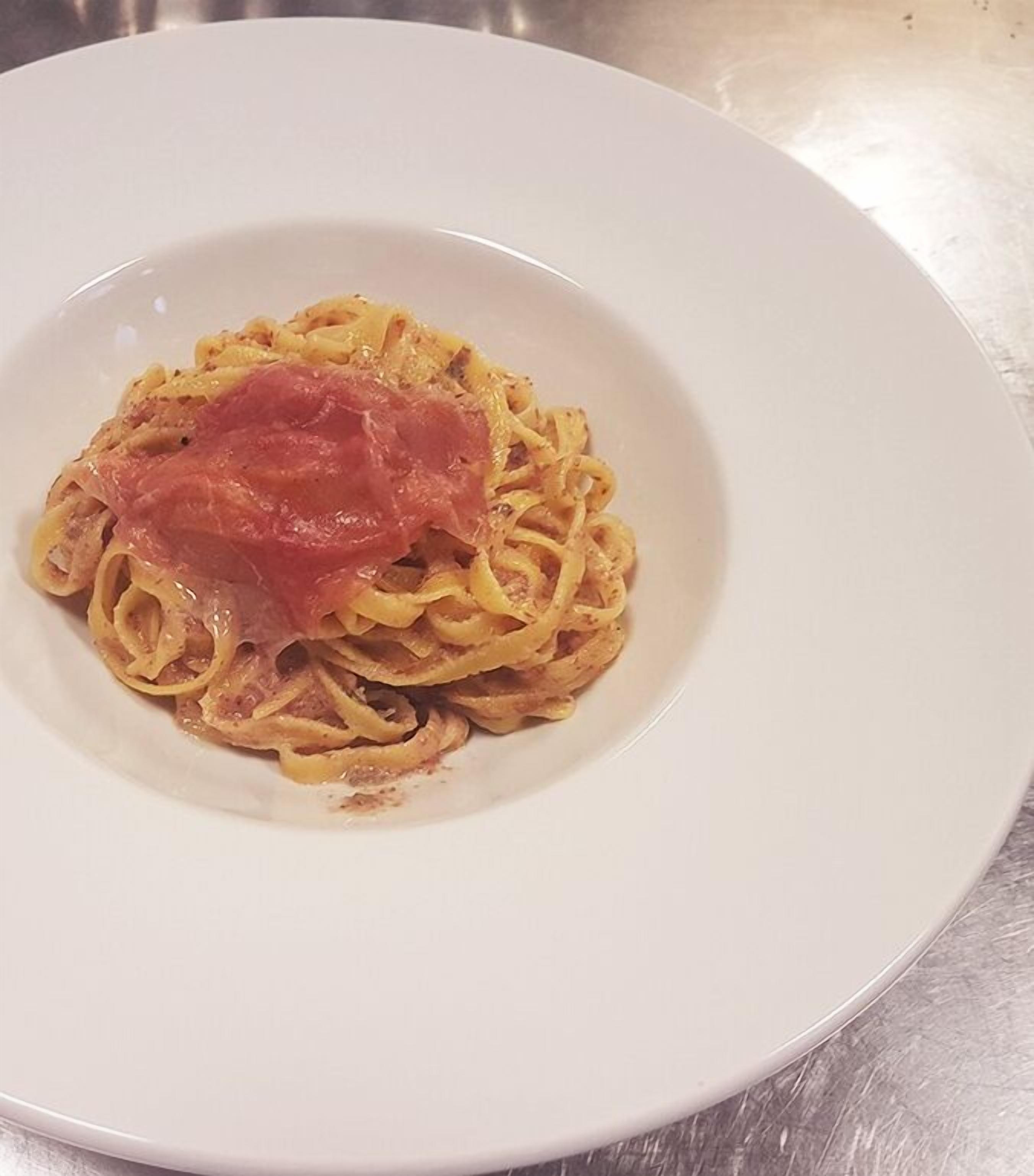 Un plato de espagueti con una rodaja de tomate encima.
