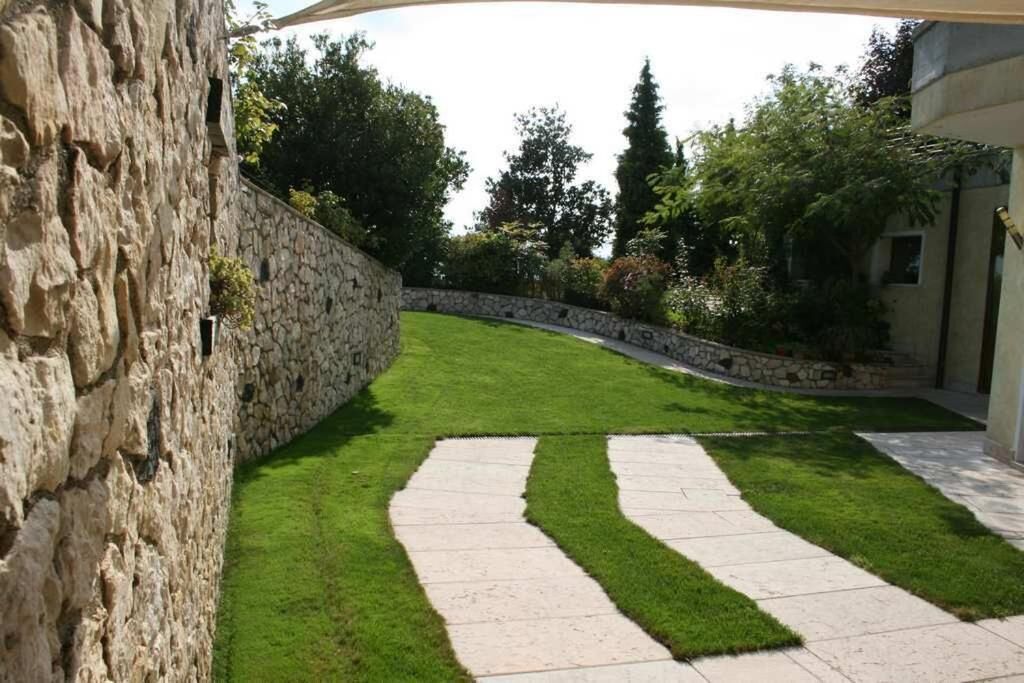 Un muro de piedra, un césped cuidado y un sendero pavimentado.