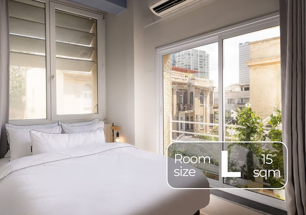 A hotel room with a bed, a window with a view of buildings, and a text overlay indicating the room size and price per night. - Monochrome Rothschild - Smart Hotel by Loginn Tel Aviv (Tel Aviv)