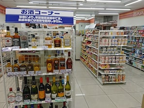 A liquor store aisle with various alcohol brands and a sign indicating a legal age verification requirement.