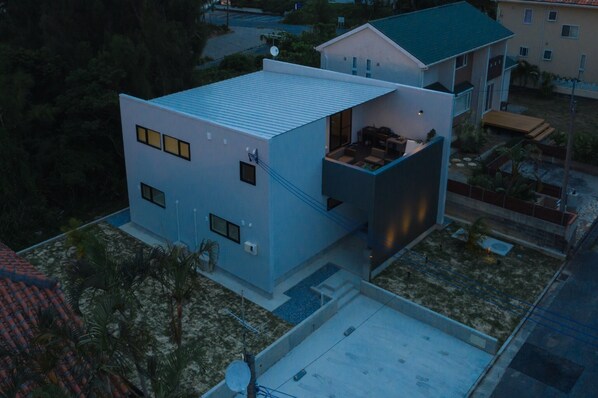 Een modern huis met twee verdiepingen, een plat dak, grote ramen en een balkon.