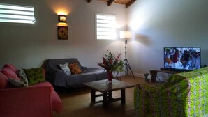 Ein Wohnzimmer mit einer Couch, einem Couchtisch, einem Fernseher und einer Lampe.