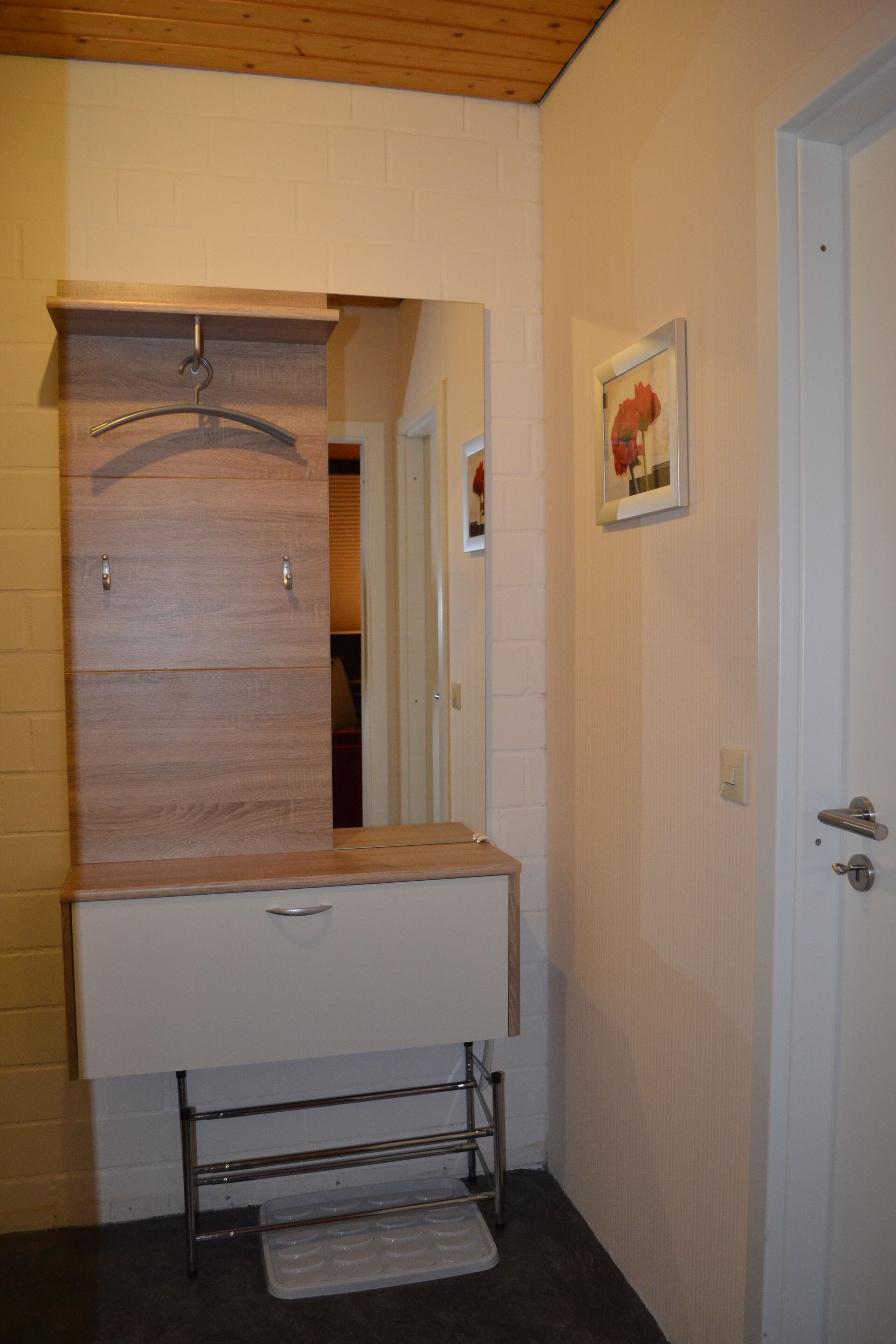 A bathroom with a wooden vanity, a mirror, and a door.