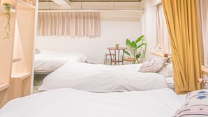 A bedroom with two beds, a small table, and a plant. - AMP FLAT Nishijin 2F (Fukuoka)