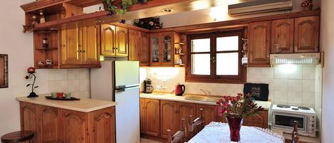 A kitchen with wooden cabinets, a central island with stools, a dining table with a vase, and a sign that reads "HOME VENTURES".
