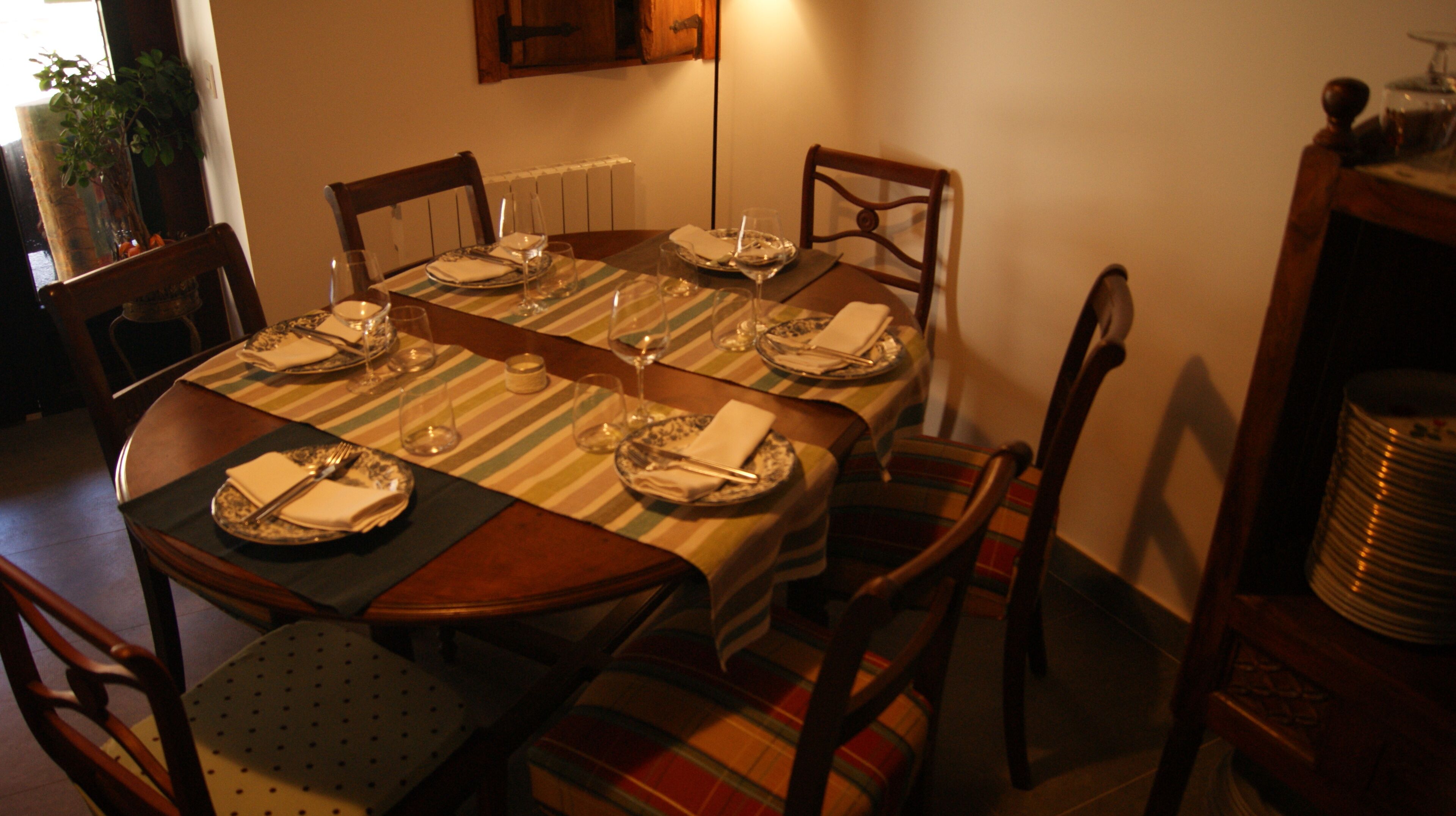 A dining table set for six with striped placemats, plates, and cutlery.