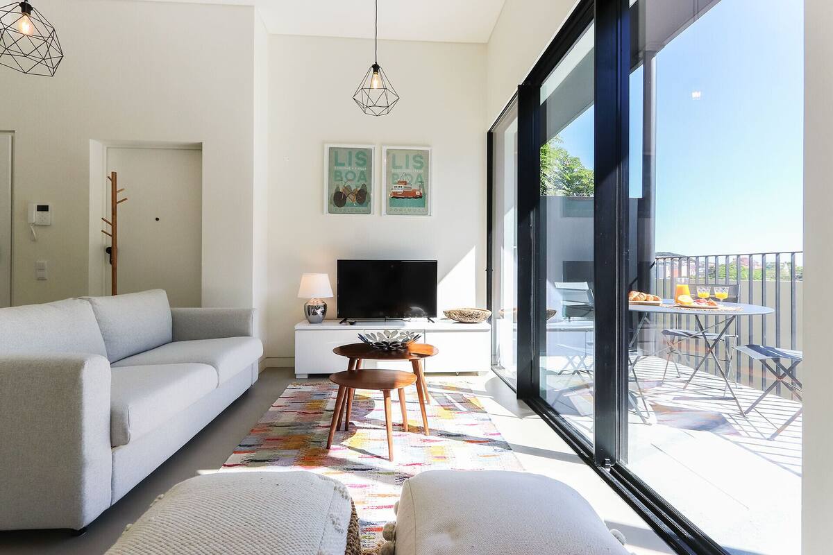 Ein modernes Wohnzimmer mit Sofa, Fernseher und Essbereich mit Tisch und Stühlen.