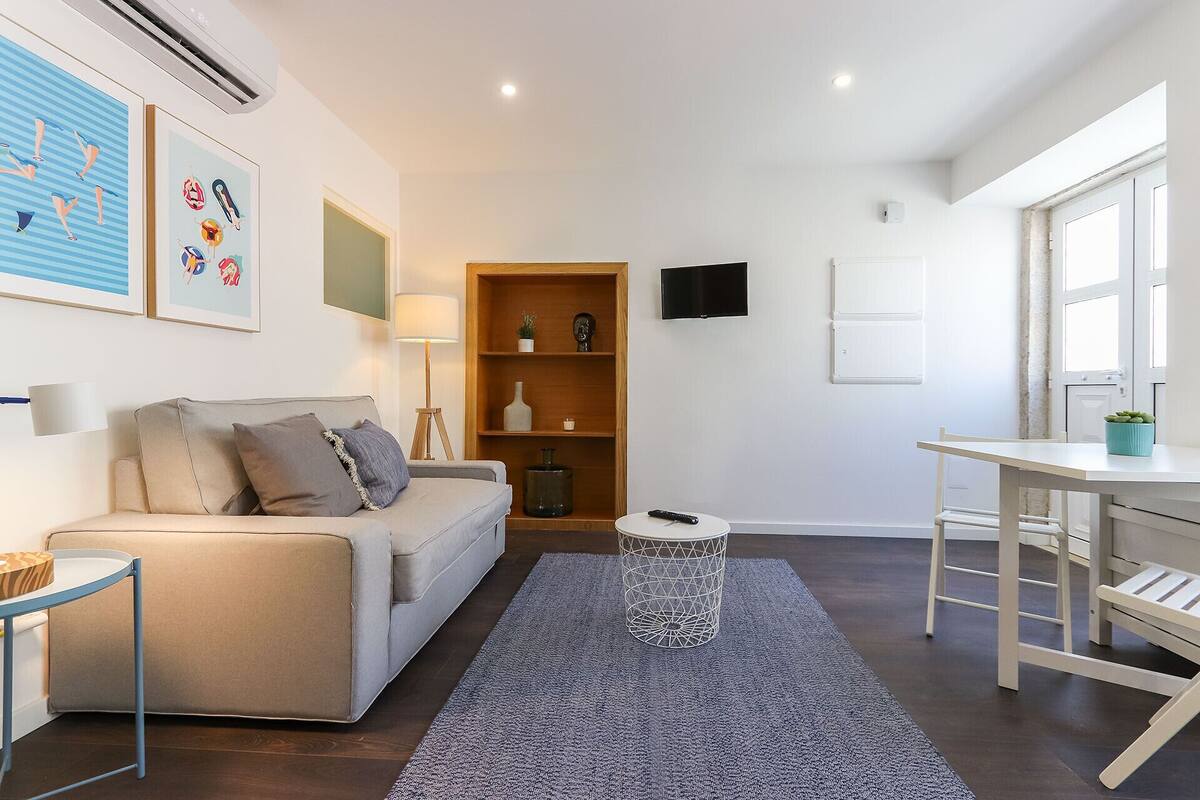 A modern living room with a sofa, a small round table, a TV, and a bookshelf.