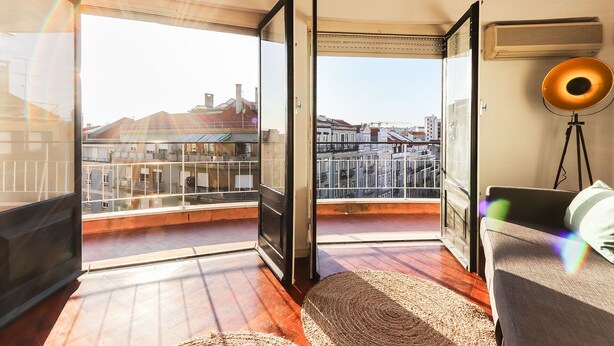 Ein Zimmer mit großem Fenster, Deckenventilator und Blick auf Gebäude.