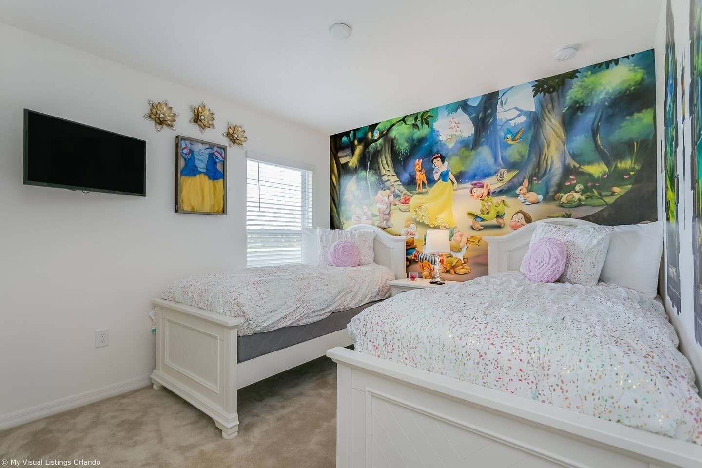 A bedroom with two beds, a TV, and a large forest-themed mural on the wall.