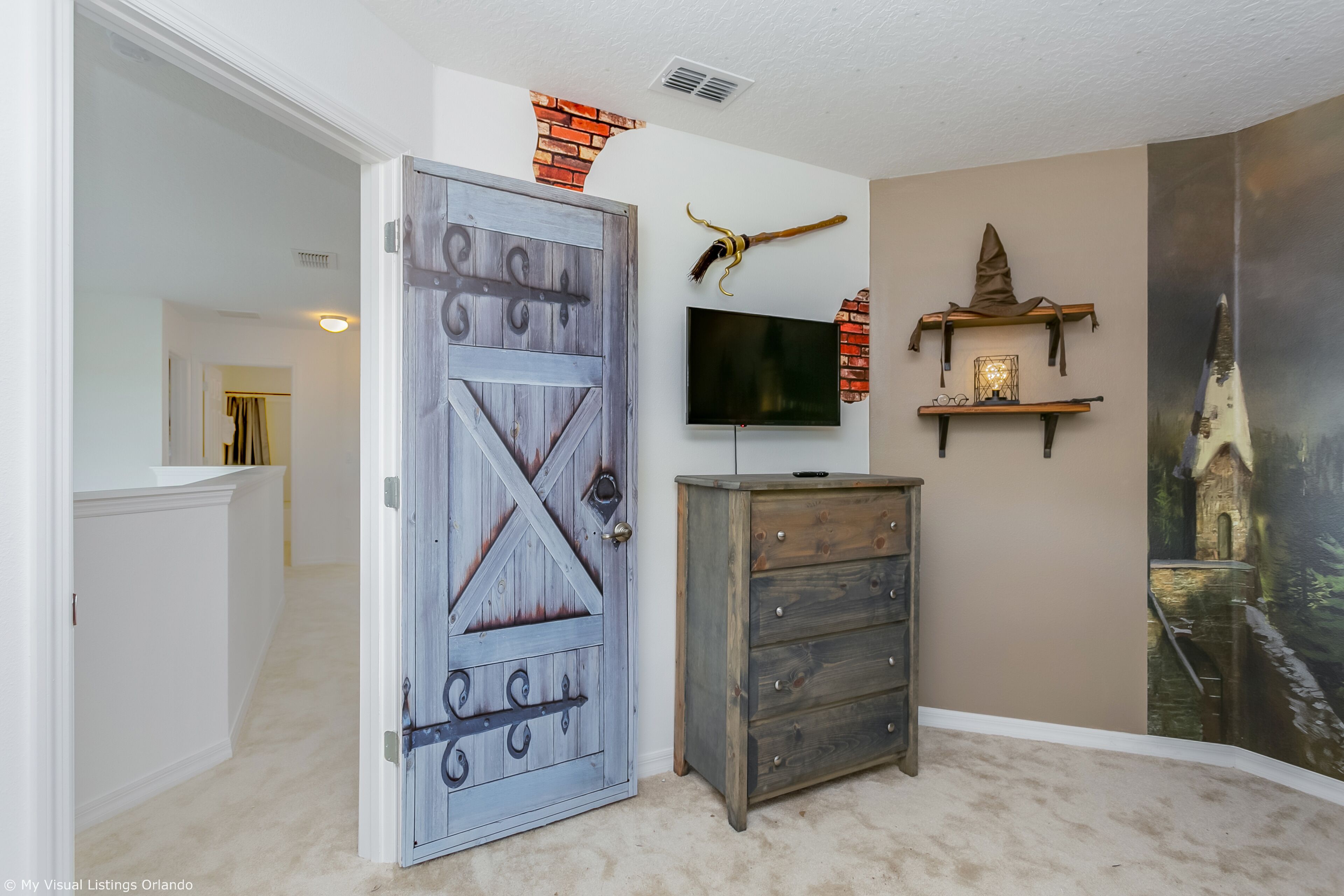 A room with a rustic door, a flat-screen TV, and a wall mural.