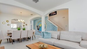 Ein modernes Wohnzimmer mit Sofa, Couchtisch, Essbereich mit Stühlen und einer Treppe.