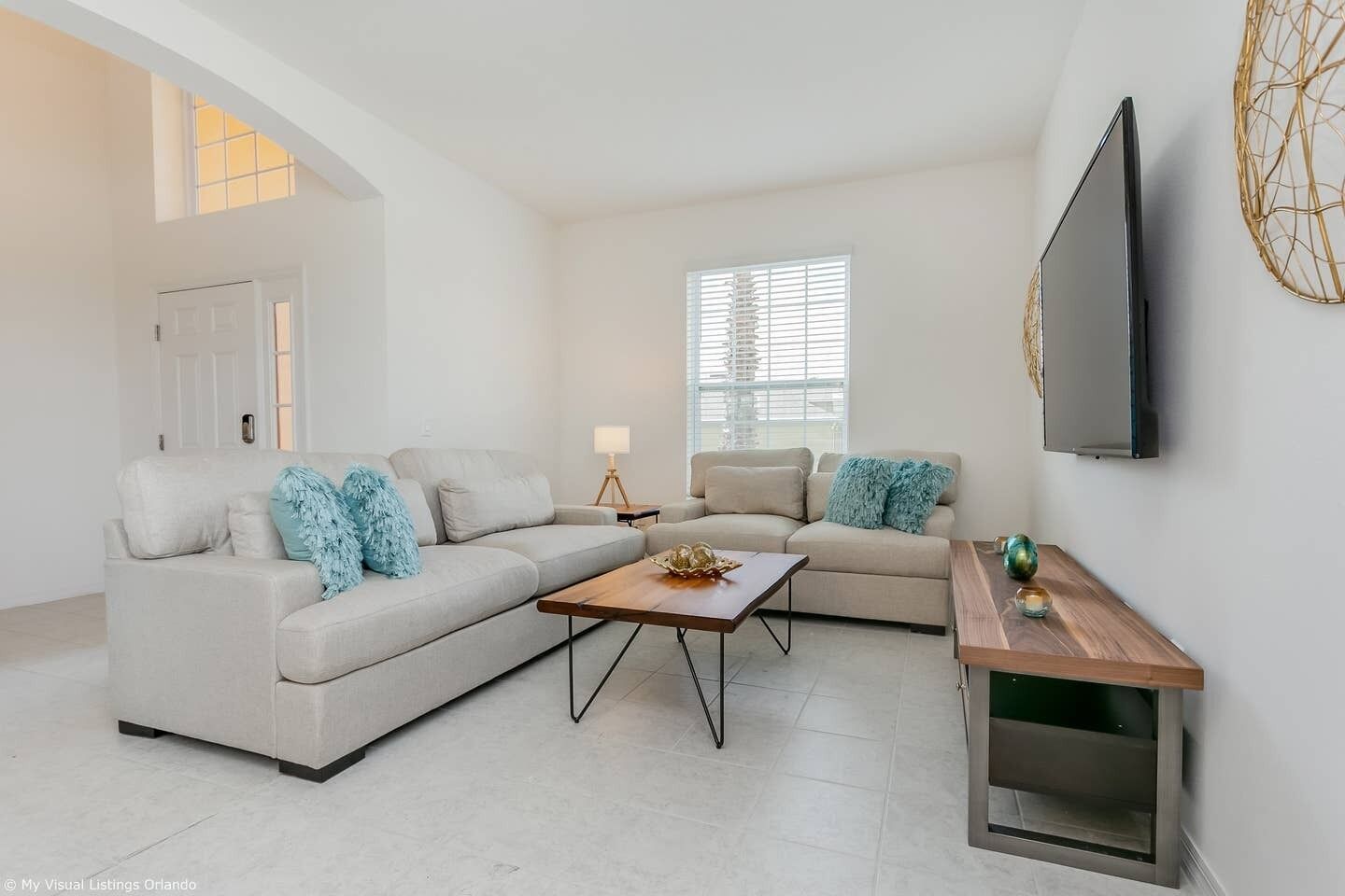A modern living room with a sectional sofa, a coffee table, and a TV mounted on the wall.