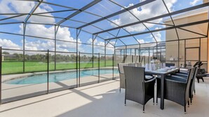 Ein überdachter Außenbereich mit Pool, Sitzgelegenheiten im Freien und Blick auf die Landschaft.
