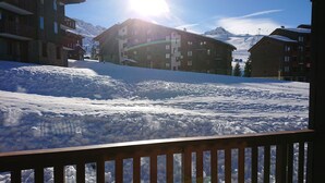 A snow-covered slope with buildings in the background.