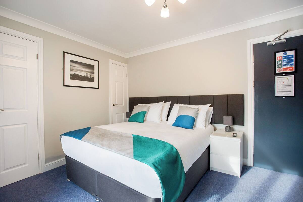 A neatly arranged hotel room with a bed, bedside table, and a framed picture on the wall.