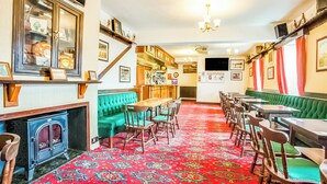 A traditional inn with a long dining area, green upholstered seating, and a patterned carpet.
