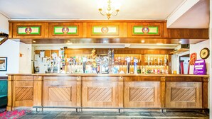 A bar area with wooden cabinets, a variety of bottles, and a red patterned carpet.