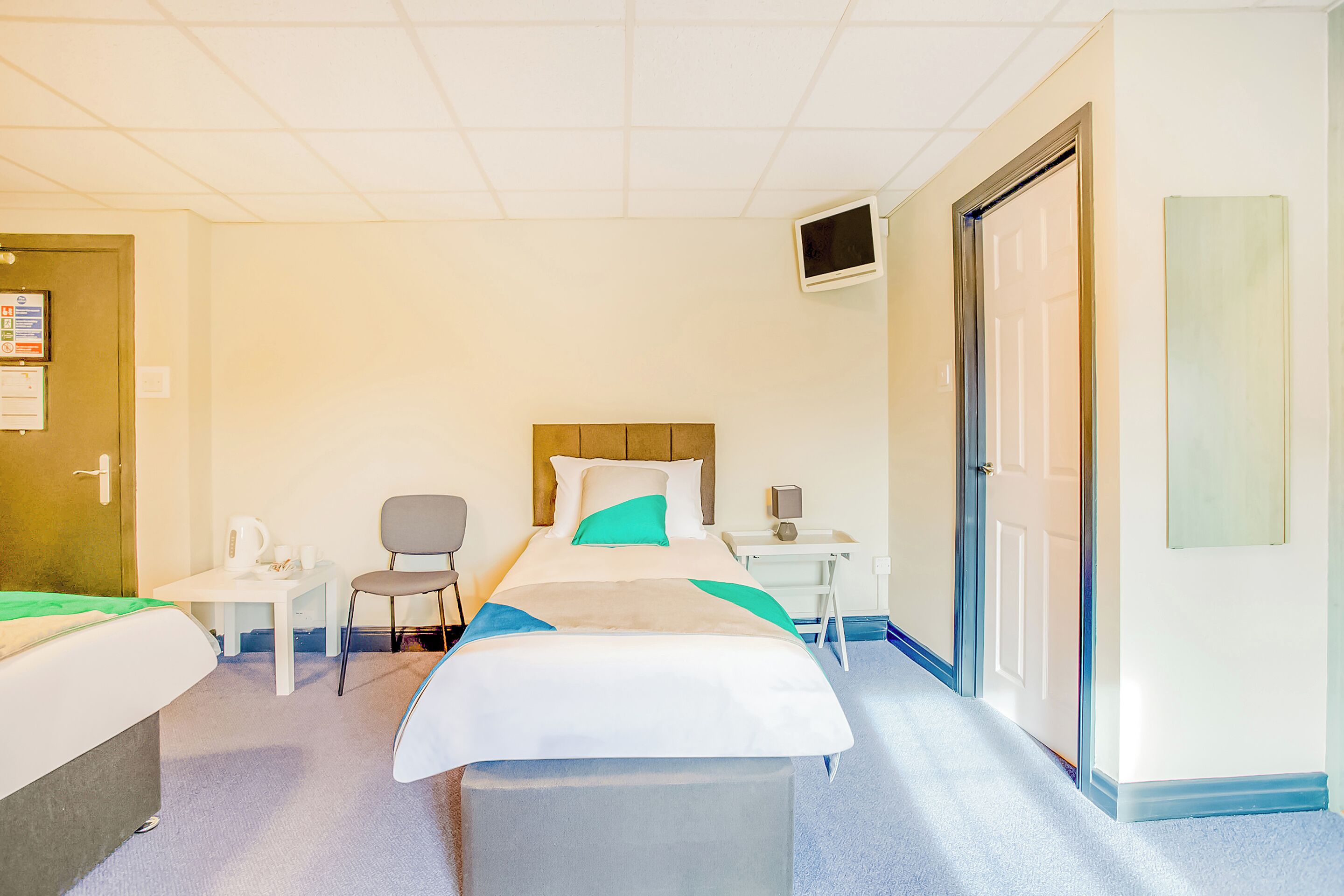A hotel room with two beds, a desk, a chair, and a television on the wall.