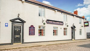 A white building with a sign reading "The Village Inn."