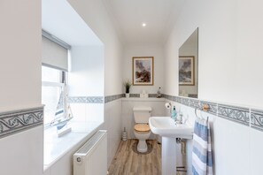 A bathroom with a toilet, sink, and window. - The Steadings - by StayDunfermline (Dunfermline)