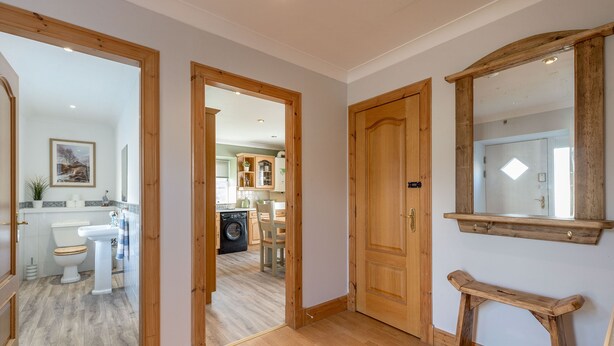 A hallway with wooden doors leading to a bathroom and a kitchen area.