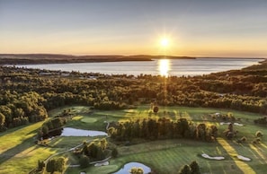 A golf course with a lake, surrounded by dense forest, and a sunset in the background. - Private Crystal Lake Beach, walk downtown Beulah! Biweekly & ￼monthly discounts. (Beulah)