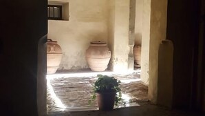 An arched doorway leading to a courtyard with terracotta pots and a potted plant. - Ostello del Bigallo - Bigallo Hostel (Bagno a Ripoli)