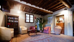 A cozy living room with a rustic ceiling, a bookshelf, a potted plant, and a large vase. - Ostello del Bigallo - Bigallo Hostel (Bagno a Ripoli)