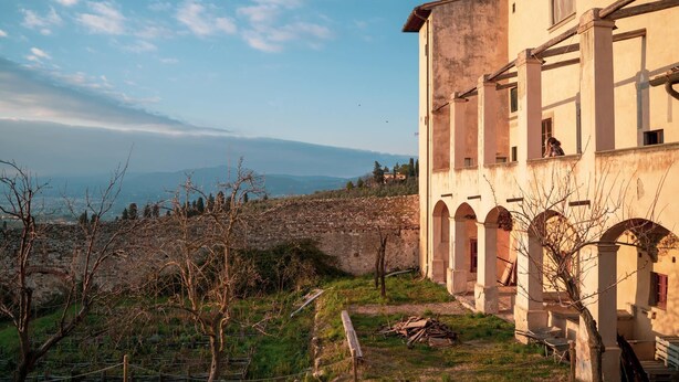 A building with arched windows and a stone wall in the background. - Ostello del Bigallo - Bigallo Hostel (Bagno a Ripoli)