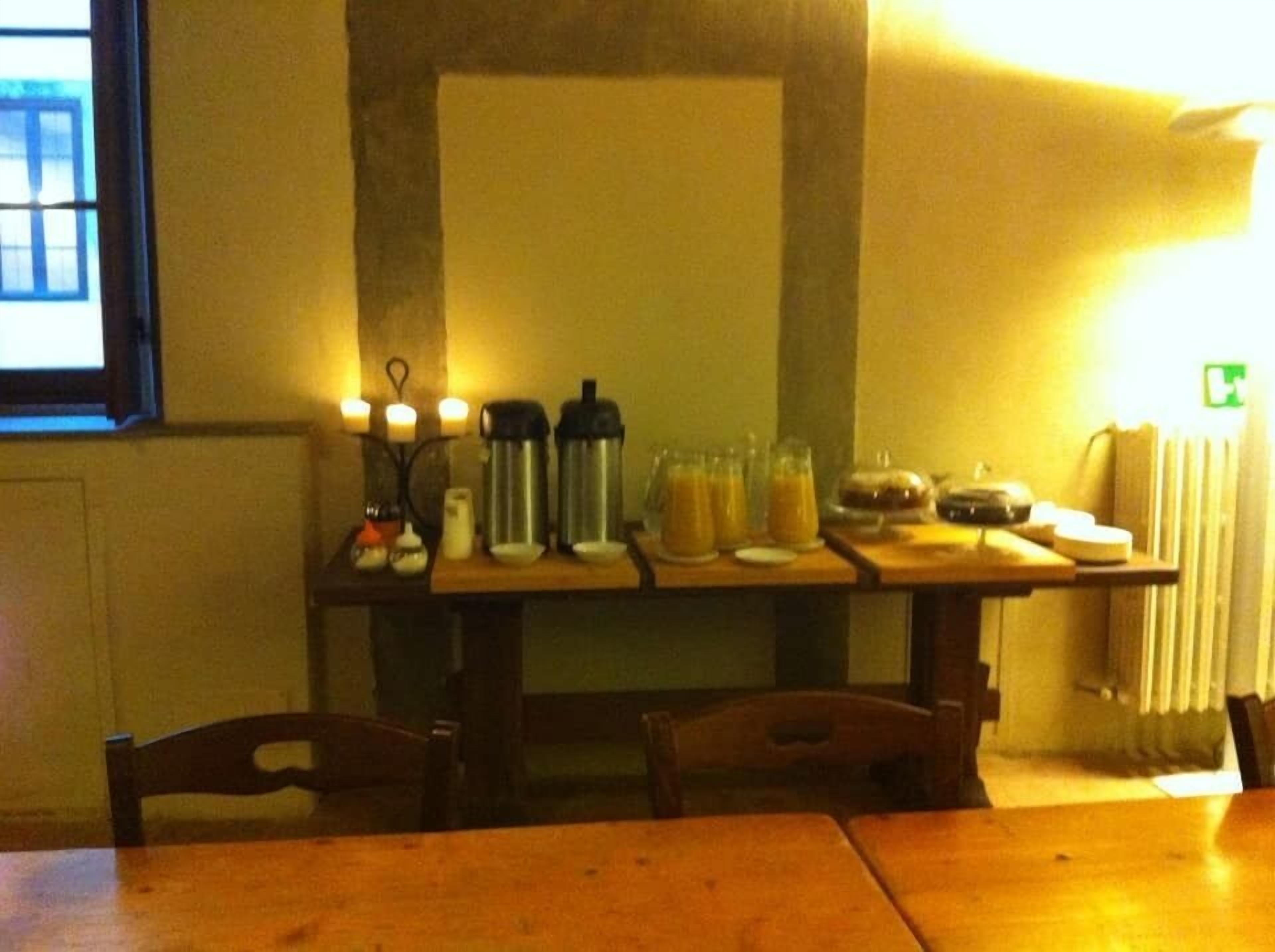 Uma mesa de jantar com velas, garrafas de água e uma cesta de pão.