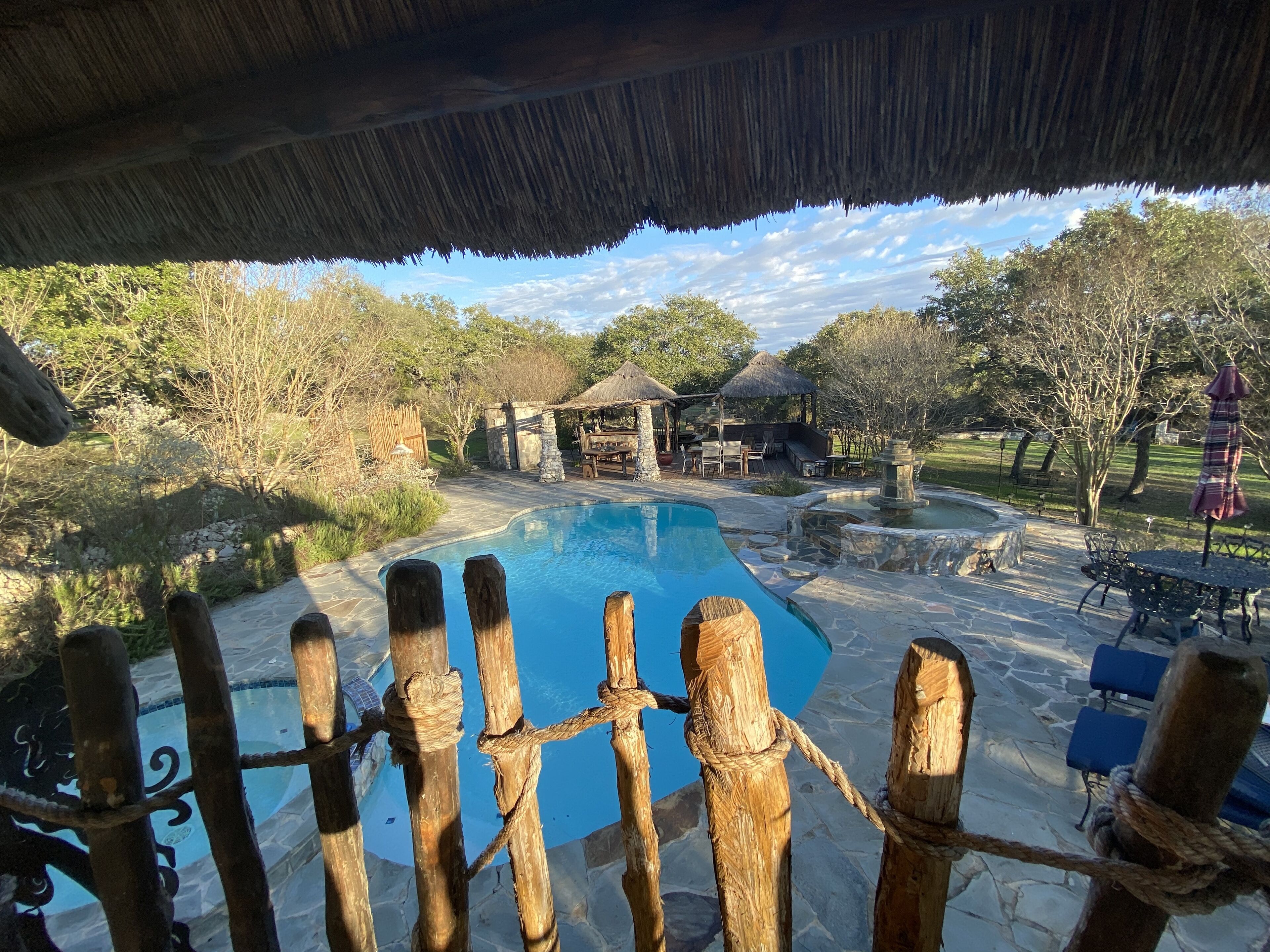 A pool area with a thatched roof, stone structures, and outdoor seating.