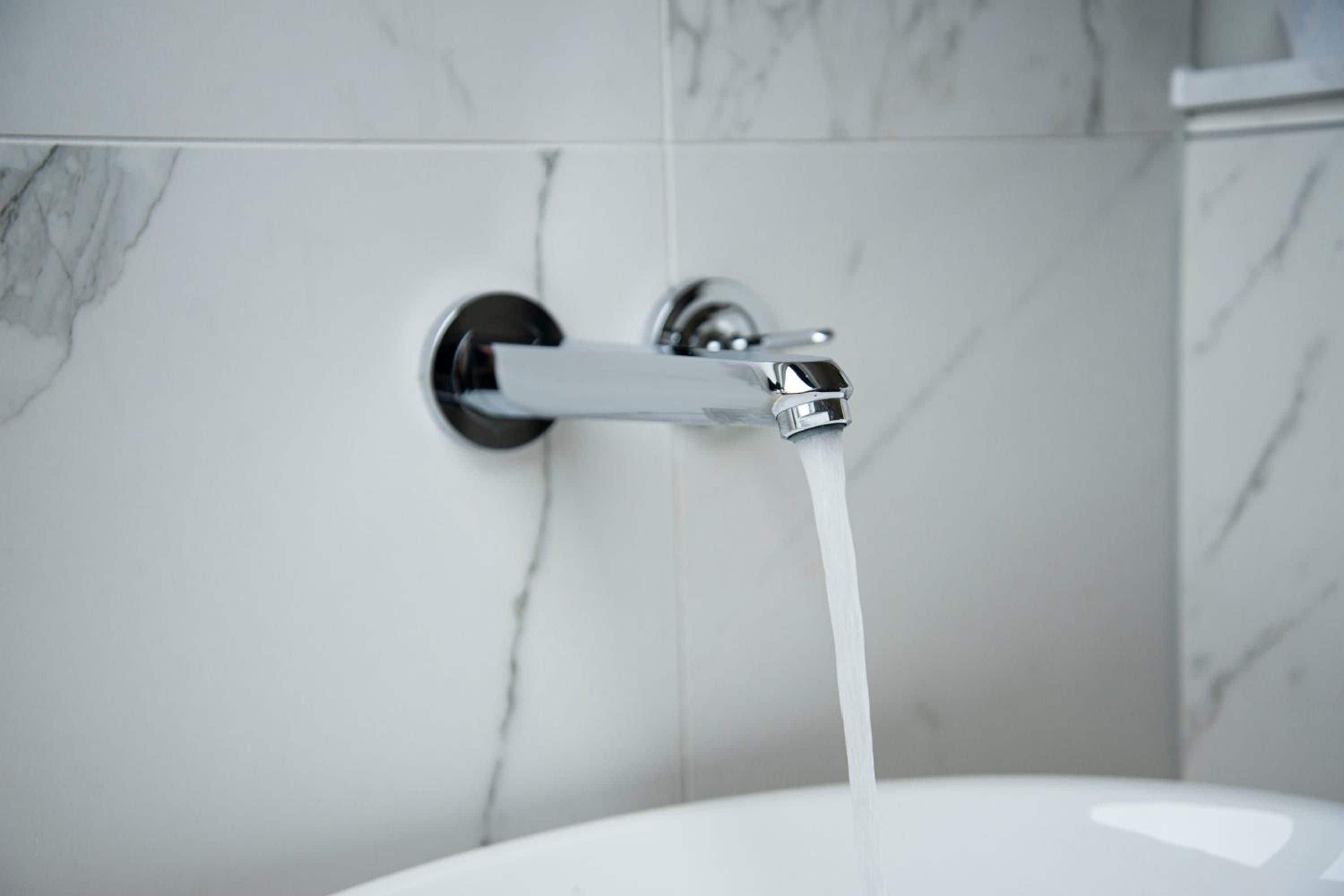 A bathroom with a modern faucet and running water.