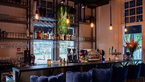 A bar area with a long counter, bar stools, and a coffee machine.