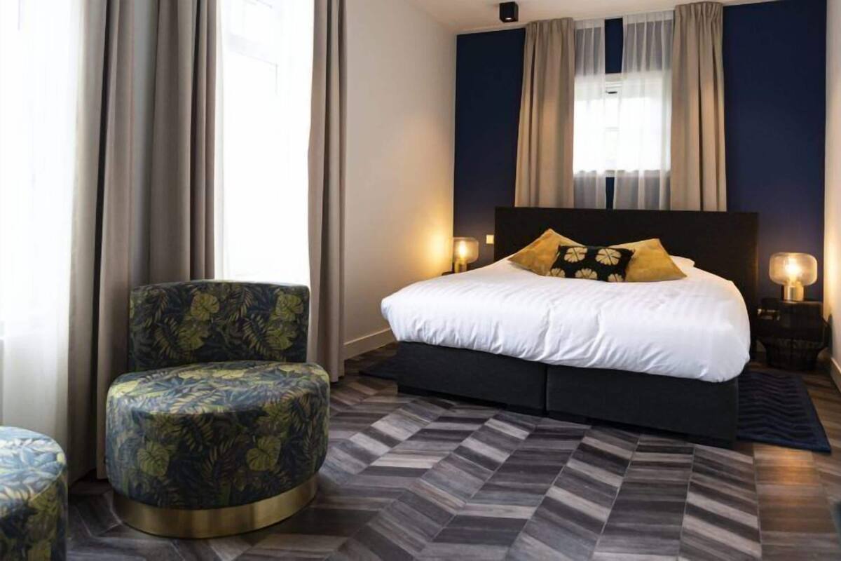 A bedroom with a bed, a chair, a rug, and curtains.