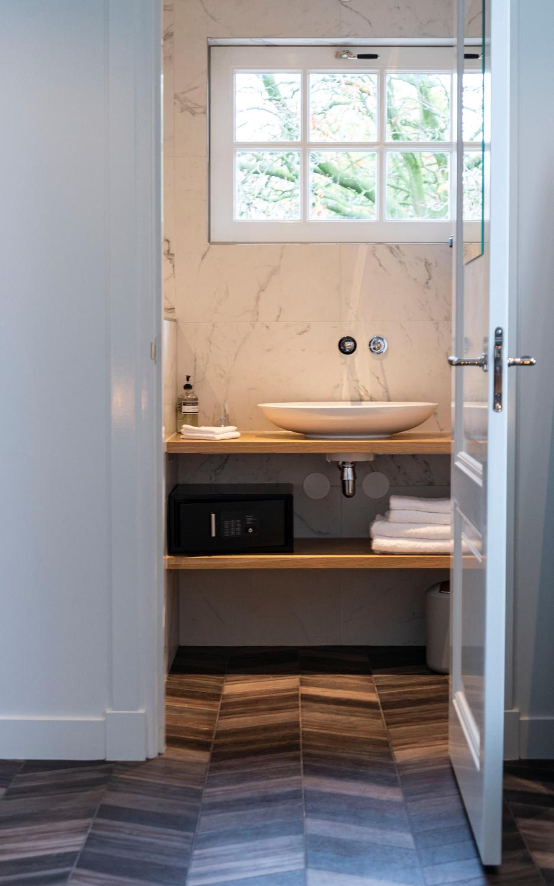 A bathroom with a marble sink, a window above the sink, and a patterned floor.