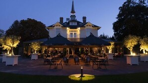 A large, stately building with a prominent tower and a covered outdoor seating area with tables and chairs.