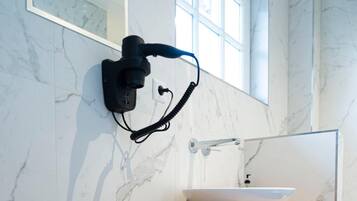 Une salle de bain moderne avec un mur en marbre, un meuble-lavabo en bois, un lavabo blanc et un porte-serviettes.