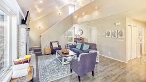A spacious living room with a fireplace, a large sofa, a coffee table, and a view of the outdoors. - Dog-Friendly, *HOT TUB*, Walk to Beach (Sisu) (Ocean Park)