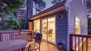 A wooden deck with a table and chairs, a covered seating area, and a glass door leading to an interior space with a dining area. - Dog-Friendly, *HOT TUB*, Walk to Beach (Sisu) (Ocean Park)