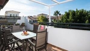 An outdoor patio with a table and chairs, potted plants, and a view of buildings and trees. - Lovely apartment for 7 guests with pool, WIFI, A/C, TV and terrace (Torremolinos)